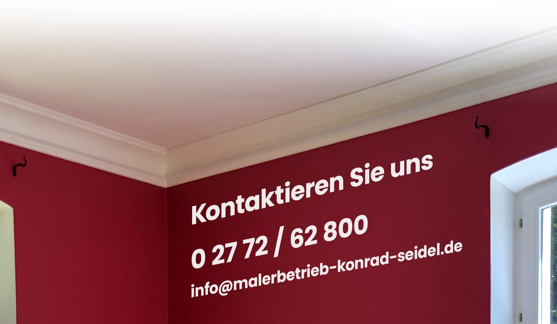 Frisch gestrichenes Zimmer in Rot mit Kontaktdaten: Telefon 0 27 72 / 62 800, E-Mail info@malerbetrieb-konrad-seidel.de
